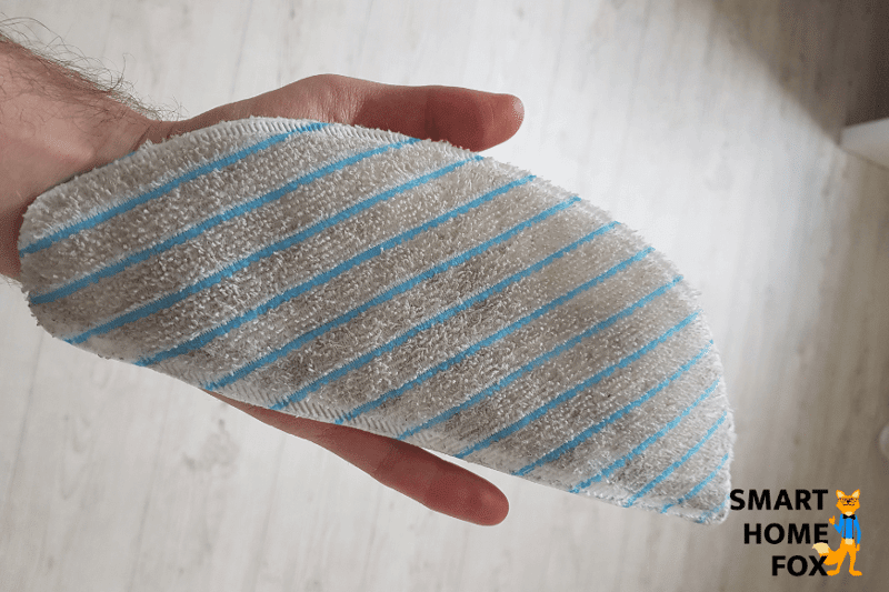 В руке грязная салфетка робота-пылесоса с функцией влажной уборки